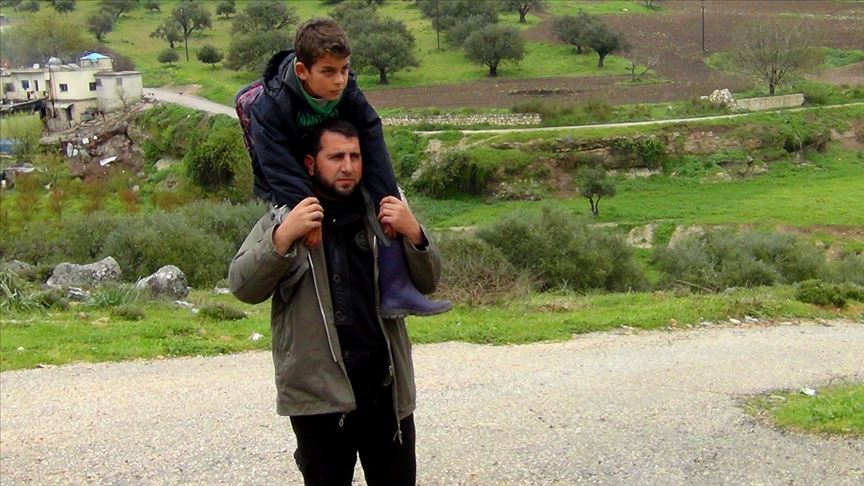 زحفاً أوعلى أكتاف والده.. طفل سوري يستكمل تعليمه رغم الحرب
