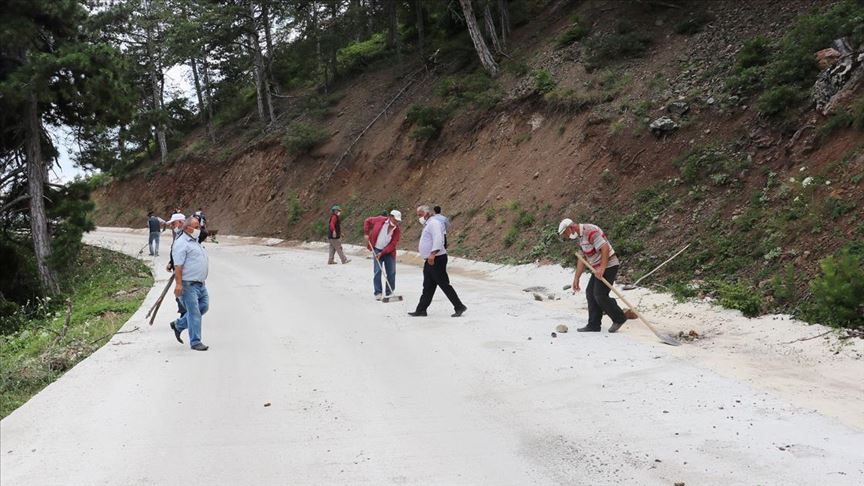 Yeni yapılan köy yolunu zarar görmesin diye kürek ve süpürgeyle temizliyorlar