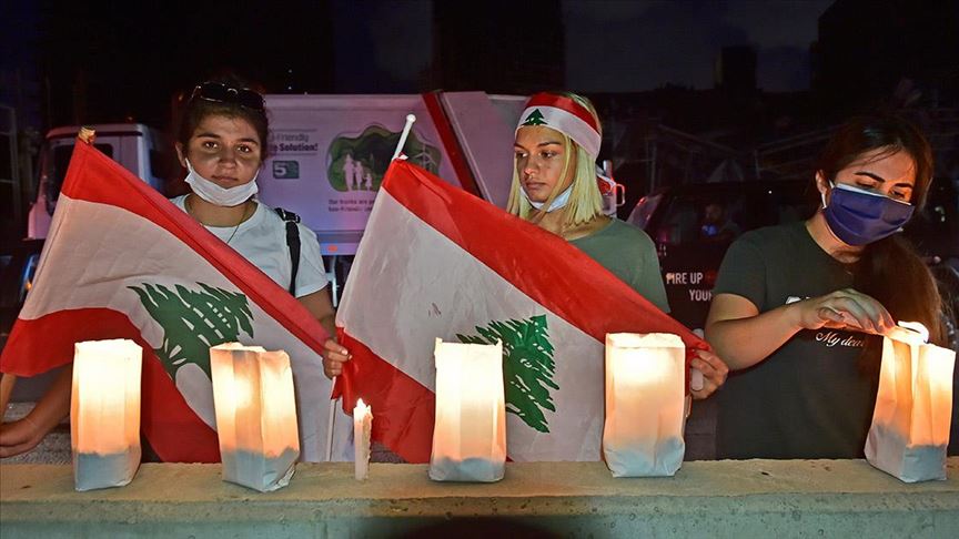 بشموع وعلم لبنان.. العشرات يتجمعون في محيط انفجار بيروت