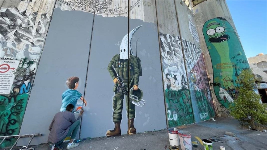 فلسطيني يعكس العنصرية الإسرائيلية على الجدار الفاصل