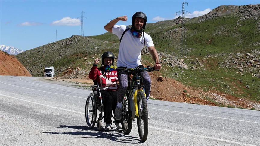 Bisikletine monte ettiği tekerlekli sandalyeyle engelli komşusunun tur hayalini gerçekleştirdi