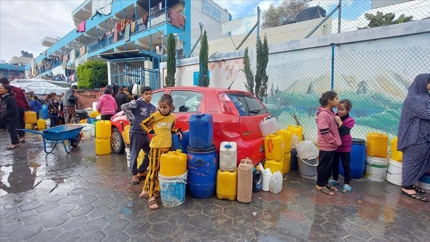 Palestinians wait in water lines under shadow of bombs