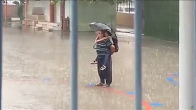 Adana'da bir kişi sağanakta sırtına aldığı torunuyla İstiklal Marşı'nı okudu 