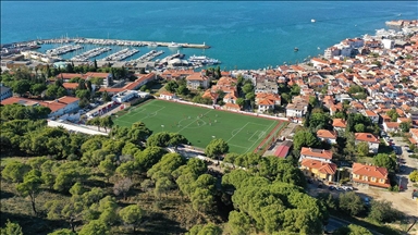 Ağaçların gölgesinde deniz manzaralı tribünde maç keyfi