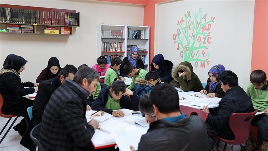 Ebeveynler çocuklarıyla kitap okumak için okulun kütüphanesinde buluşuyor