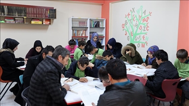 Ebeveynler çocuklarıyla kitap okumak için okulun kütüphanesinde buluşuyor