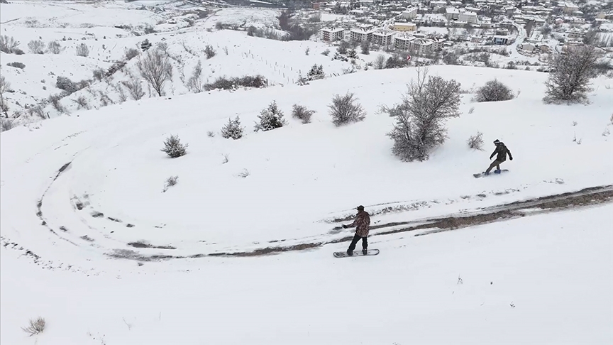 Erzincan'ın tarihi Kemah ilçesinde snowboardcular dağdan ilçe merkezine kayarak indi