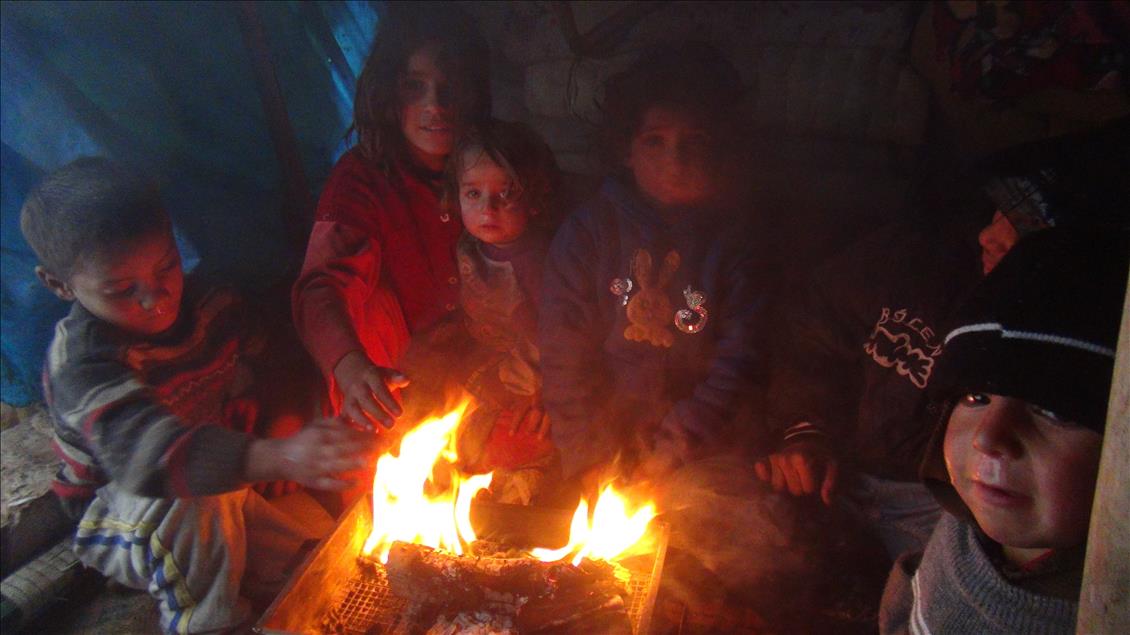 Suriyeli mülteciler çadırda ateş yakarak ısınmaya çalışıyor