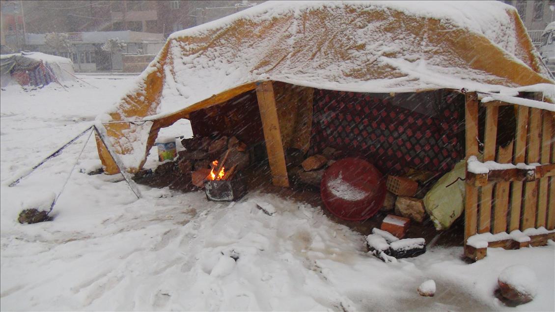 Suriyeli mülteciler çadırda ateş yakarak ısınmaya çalışıyor