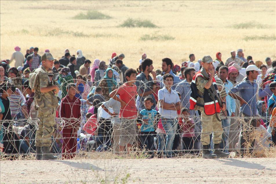 Syrians fleeing the war in their country wait to cross into Turk