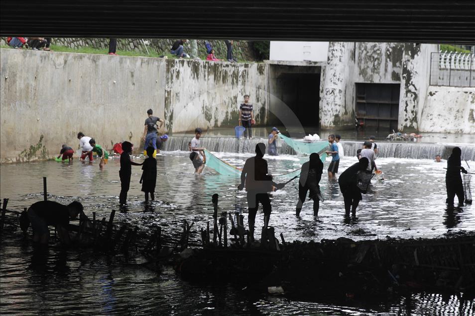 Jakartans catch drifted fishes at water gate after heavy rainfall