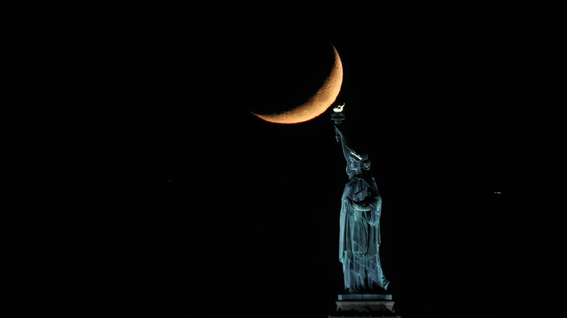 Crescent Moon sets behind the Statue of Liberty in NYC