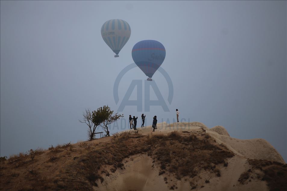 Hot air balloons glide over foggy landscape in Cappadocia