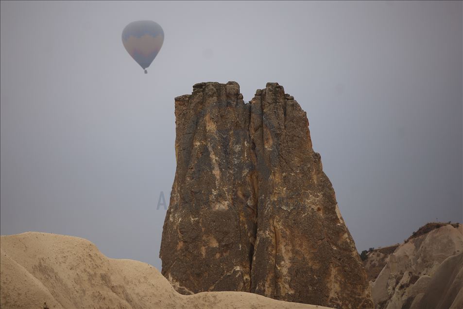 Hot air balloons glide over foggy landscape in Cappadocia