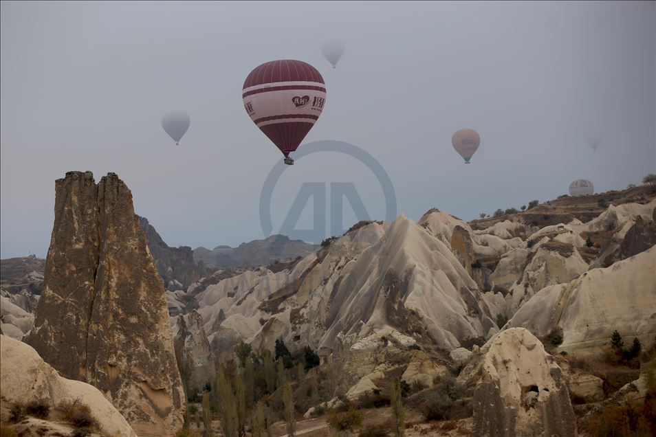 Hot air balloons glide over foggy landscape in Cappadocia