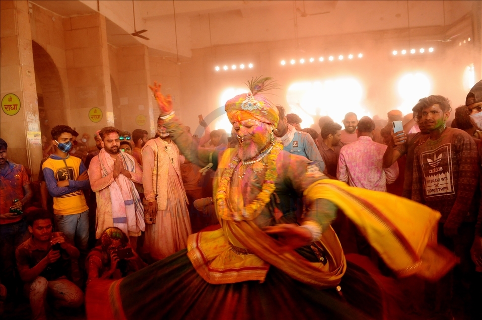 BARSANA, INDIA -MARCH 23, 2021 : Hindu devotees dance as colored powder is thrown on them at Ladali, or Radha temple, at the legendary hometown of Radha, consort of Hindu God Krishna, during Lathmar holi, in Barsana on the outskirts of Mathura in the nort