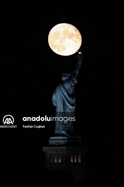 Full moon rises behind The Statue of Liberty