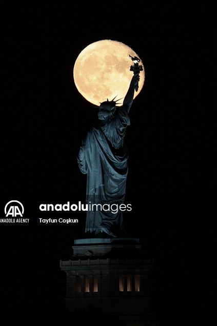 Full moon rises behind The Statue of Liberty