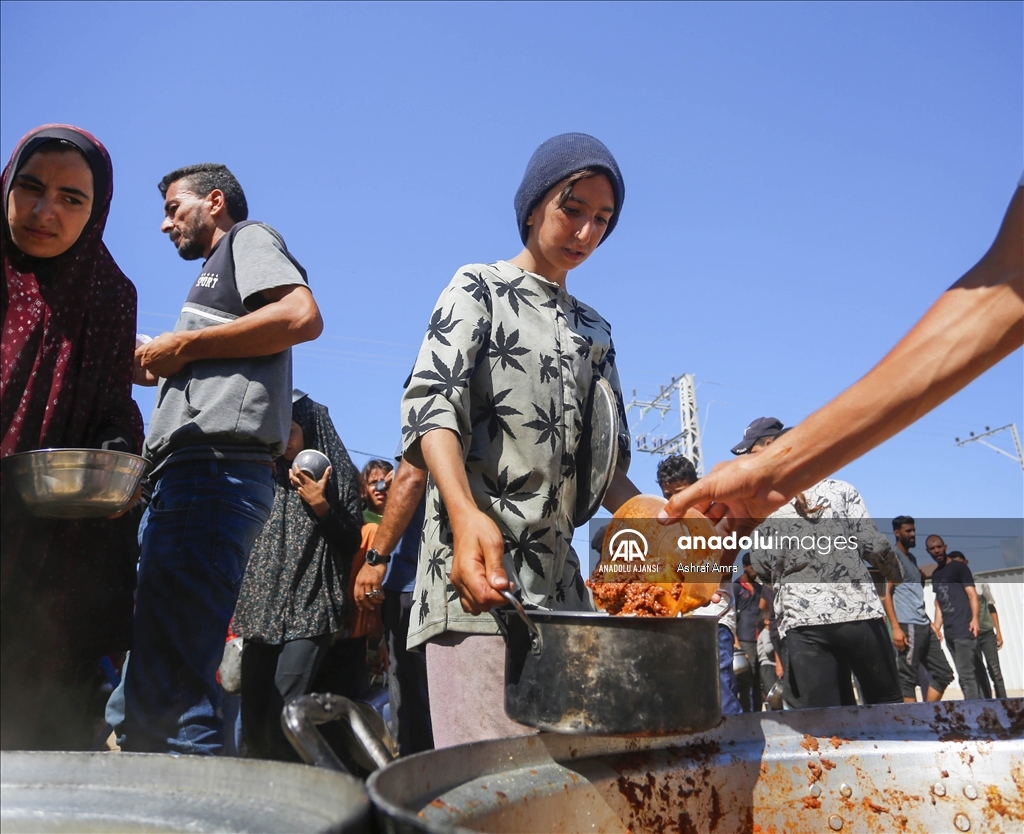 Gazze'deki Filistinliler bir kap sıcak yemek için kuyrukta bekliyor