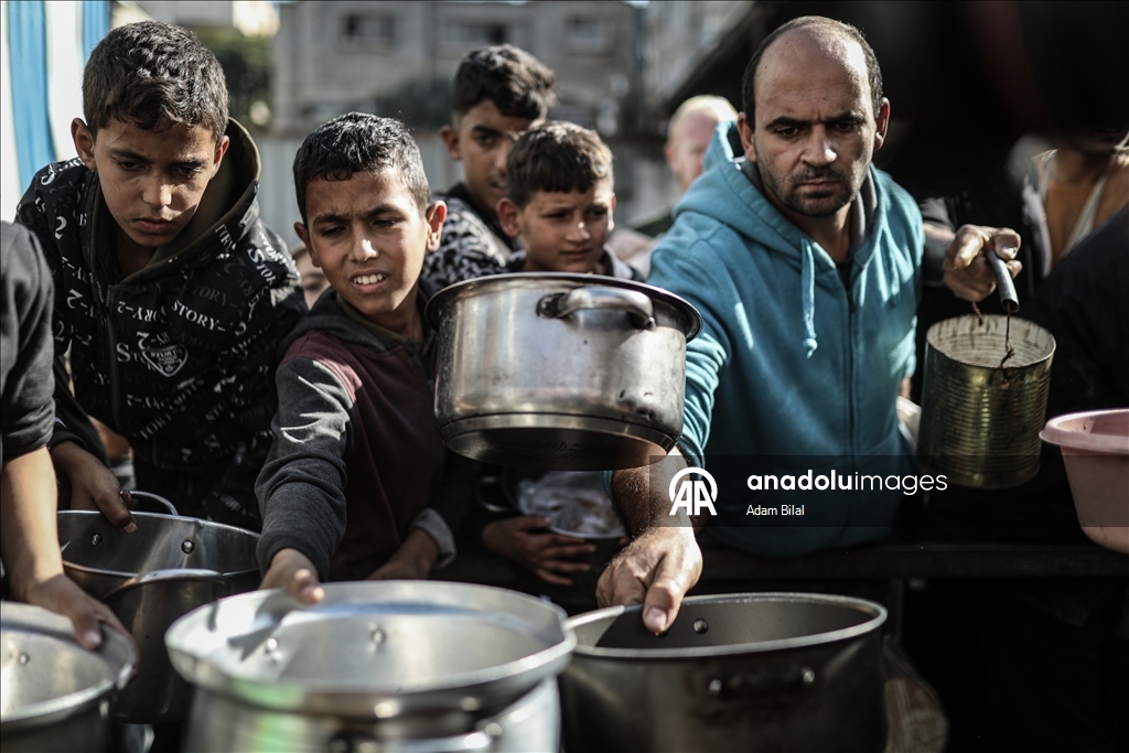 Displaced Palestinians receive hot meal in Deir al-Balah